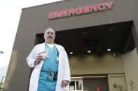 Dr. Stephen Anderson, a physician who works in the Emergency Department at the MultiCare Auburn Medical Center in Auburn, Wash., holds his mask and face shield as he poses for a photo before starting his shift, Tuesday, March 17, 2020, in Auburn, Wash., south of Seattle. Anderson said he writes messages on his shields to identify them as his, and this morning he chose the phrase "Stay Safe." “There just are not enough masks to go around at my hospital,” said Dr. Anderson. "I've got a two-day supply of masks so we're trying to be conservative. You get one in the morning. You clean it and reuse it." (AP Photo/Ted S. Warren)