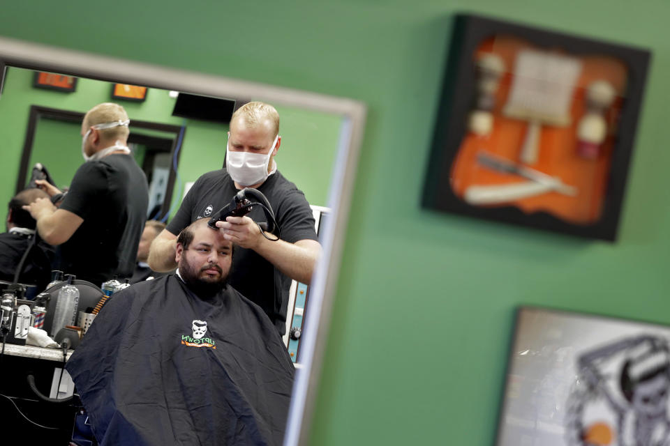 Jeff Guebara gets his hair cut by Roman Naumenko at Uptown Barbershop Friday, May 8, 2020, in Phoenix. Hair salons and barbershops across Arizona began reopening Friday after being closed for more than a month by order of the governor due to the COVID-19 Coronavirus outbreak. Clients will not be returning to the same businesses as most will be implementing social distancing measures like making people wait in their car. (AP Photo/Matt York)