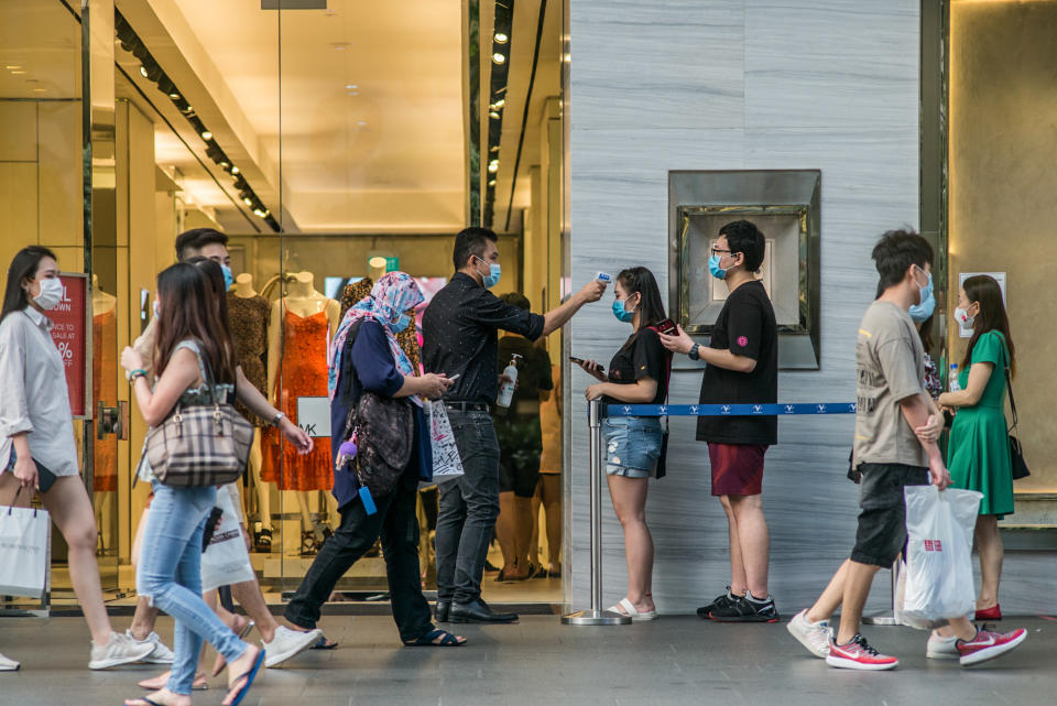 SINGAPORE - 2020/07/25: People wearing face masks are scanned for their temperatures before entering a shopping mall  along Orchard Road, a famous shopping district in Singapore. As of 26 July 2020, the total number of confirmed COVID-19 cases in Singapore are at 50,369. (Photo by Maverick Asio/SOPA Images/LightRocket via Getty Images)