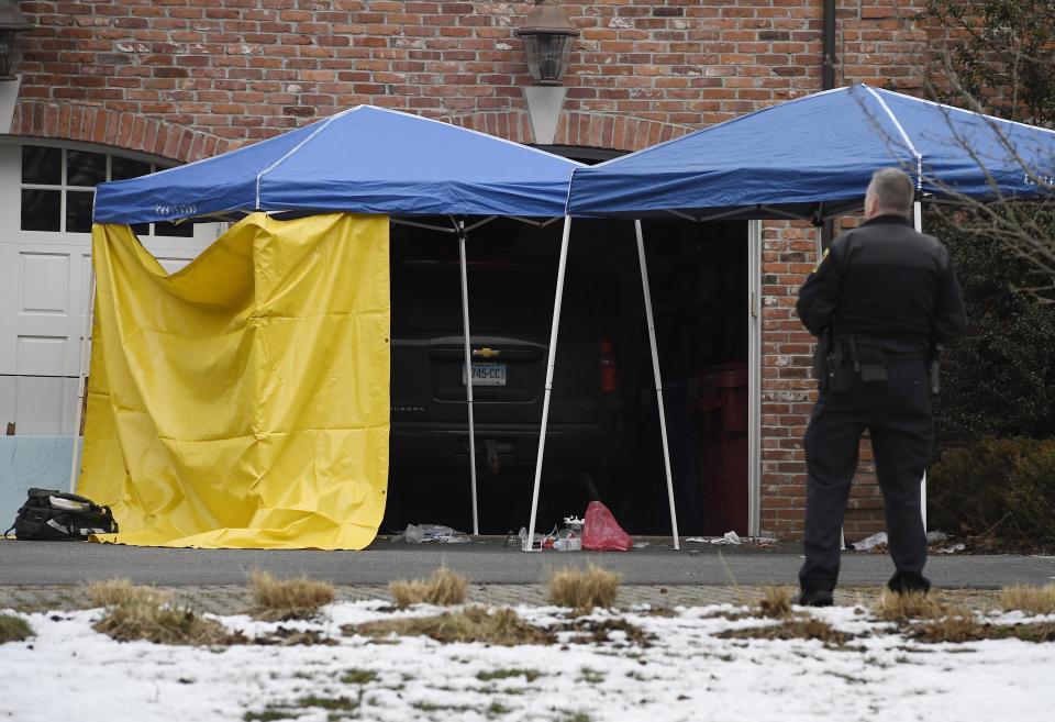 A police officer watches over an area outside of the garage to Fotus Dulos' home, Tuesday, Jan. 28, 2020, in Farmington, Conn. A dispatcher from the Farmington police said officers had responded to Dulos' home and he was later transported to the hospital (AP Photo/Jessica Hill)