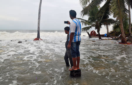 A man uses his mobile phone to take photographs of tides on the shores of the Arabian Sea, after flooding caused by Cyclone Ockhi in the coastal village of Chellanam in the southern state of Kerala, India, December 2, 2017. REUTERS/Sivaram V