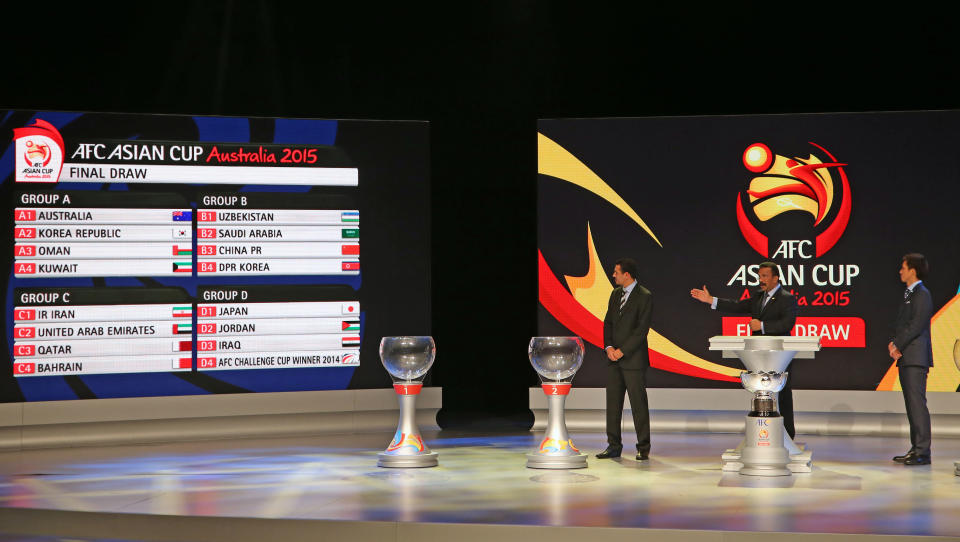 AFC General Secretary Dato' Alex Soosay, center, and Japan's Takashi Fukunishi, right, and Iraq's Younis Mahmoud stand on stage following the Asian Football Confederation draw for the 2015 Asian Cup at the Sydney Opera House ground in Sydney, Wednesday, March 26, 2014. Australia hosts the tournament that will be played in Jan. 2015. (AP Photo/Rick Rycroft)