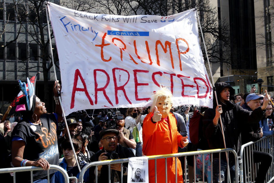 Trump opponents, with a sign that says Finally Trump Arrested, outside the Manhattan district attorney's office on Tuesday.