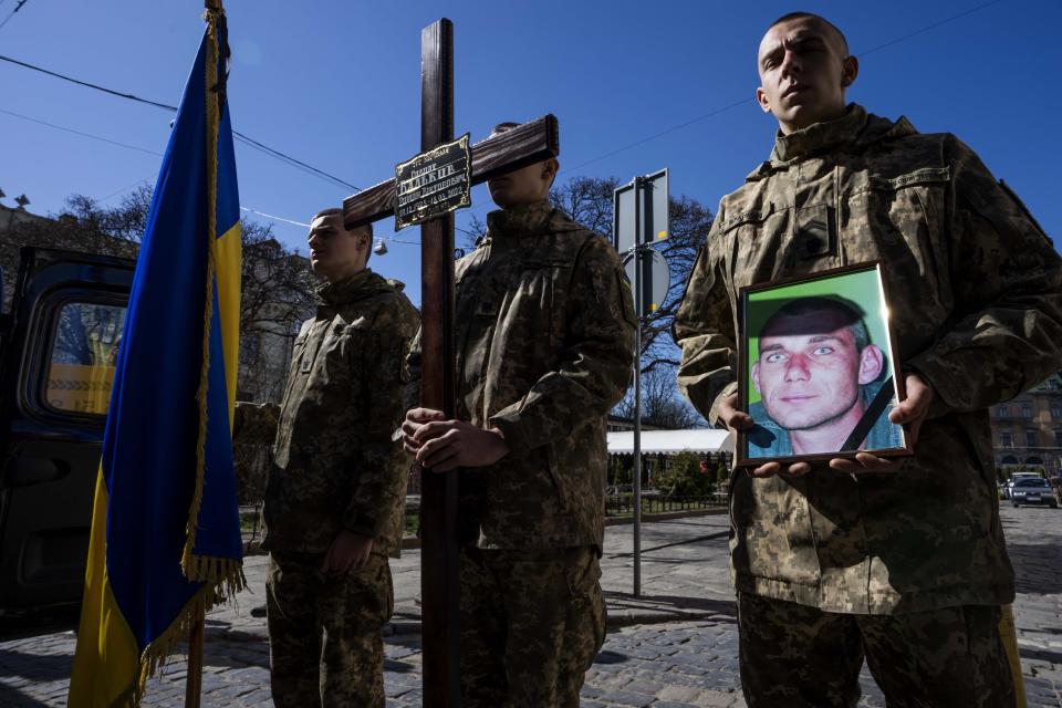 A Ukrainian soldier holds the photograph of 47-year-old soldier Roman Valkov, during his funeral ceremony, after being killed in action, at the Holy Apostles Peter and Paul Church in Lviv, western Ukraine, Monday, March 28, 2022. The more than month-old war has killed thousands and driven more than 10 million Ukrainians from their homes — including almost 4 million from their country. (AP Photo/Nariman El-Mofty)
