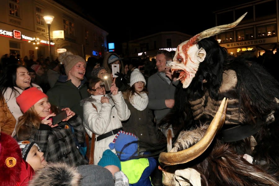 A Krampus scares spectators during a traditional Krampus run in which men and women dress up as pagan Krampus figures to scare people in Hollabrunn, Austria, Saturday, Dec.1, 2018. (AP Photo/Ronald Zak)