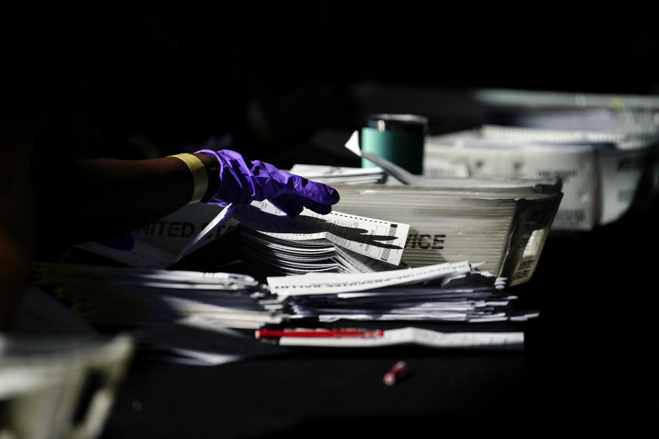 Election personnel handle ballots as vote counting in the general election continues at State Farm Arena, Wednesday, Nov. 4, 2020, in Atlanta. (AP Photo/Brynn Anderson)