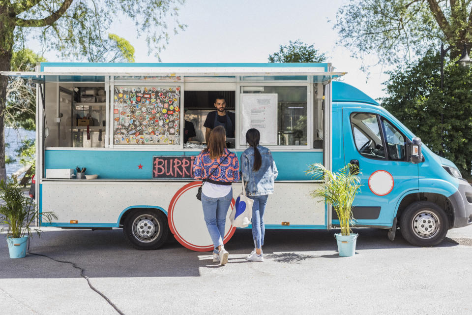 Customer at the window of a food truck placing an order with the seller