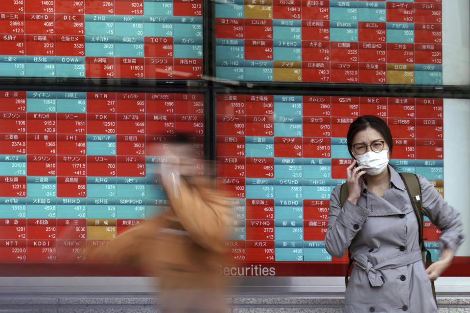 A woman talks on a mobile phone near an electronic stock board showing Japan's share prices at a securities firm in Tokyo Monday, Oct. 26, 2020. Asian shares were little changed in muted trading Monday amid widespread uncertainty over what the U.S. presidential election will portend for markets and economic policy.(AP Photo/Eugene Hoshiko)