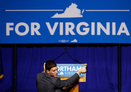 FILE PHOTO: A campaign worker adjusts a podium sign at the election night rally for Democratic gubernatorial candidate Ralph Northam on the campus of George Mason University in Fairfax, Virginia, U.S. on November 7, 2017. REUTERS/Aaron P. Bernstein/File Photo