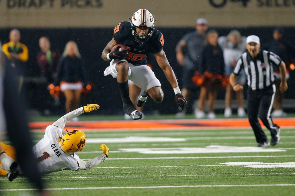 Sep 10, 2022; Stillwater, Oklahoma, USA;  Oklahoma State Cowboys running back Dominic Richardson (20) leaps over Arizona State Sun Devils defensive back Jordan Clark (1) during a college football game at Boone Pickens Stadium.  Oklahoma State won 34-17. Mandatory Credit: Bryan Terry-USA TODAY Sports
