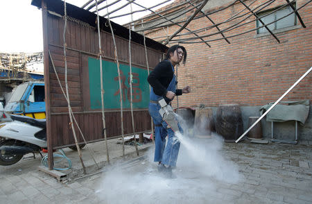 Geng Shuai, dubbed "Useless Edison" by his fans, poses to dance with a device to create theatrical fog effect with flour around him outside his workshop in Yangcun village of Baoding, Hebei province, China January 22, 2019. REUTERS/Jason Lee