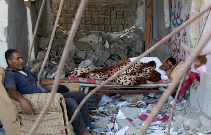 A Palestinian family rests on July 2, 2015, in the rubble of a building that was destroyed during the 50-day war between Israel and Hamas' militants in the summer of 2014, in the al-Shejaeiya neighbourhood, east of Gaza City (AFP Photo/Mohammed Abed)