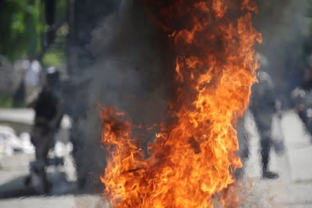 Haitian National Police (PNH) are seen behind a burning barricade during a demonstration to demand the resignation of Haitian president Jovenel Moise, in the streets of Petion Ville, Port-au-Prince