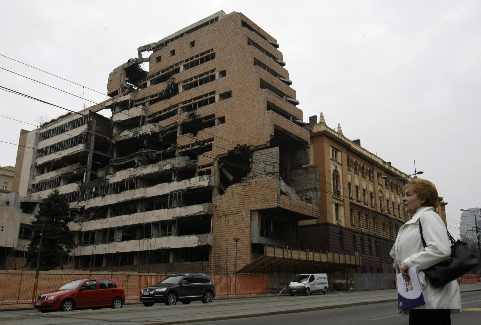 FILE- A woman walks in front of the destroyed former Serbian army headquarters in Belgrade, Serbia, March 24, 2010. Opposition groups in Serbia are planning protests against a real estate development project that will be financed by the firm of Donald Trump's son-in-law, Jared Kushner, at the site of the former Serbian army headquarters destroyed in a U.S.-led NATO bombing campaign in 1999. The Serbian government earlier this week signed a deal with a Kushner-related company for the 99-year lease of land in central Belgrade for the "revitalization" of the bombed-out buildings. (AP Photo/Darko Vojinovic, File)