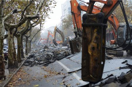 Heavy machinery are seen at work at a damaged street after Friday's explosion at a Sinopec Corp oil pipeline in Huangdao, Qingdao, Shandong Province November 24, 2013. REUTERS/Stringer