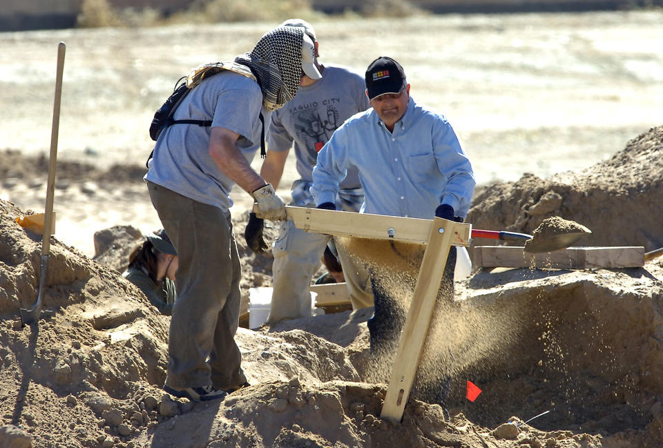 FILE - In this Feb. 25, 2009 file photo, investigators search for human remains at a 100-acre site in Albuquerque, N.M. A decade ago, Albuquerque police began unearthing the remains of 11 women and an unborn child found buried on the city's West Mesa, marking the start of a massive homicide investigation that has yet to be resolved. On the 10th anniversary of the cold case, a small group of advocates and community members plan to gather Saturday, Feb. 2, 2019, near the 2009 crime scene to remember the victims and call for more protections for marginalized and vulnerable women in New Mexico's largest city. (Pat Vasquez-Cunningham/The Albuquerque Journal via AP, File)