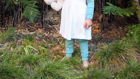 little girl in smurf 80s costume with yellow yard hair, blue leggings and long sleeve top, white dress and phrygian cap