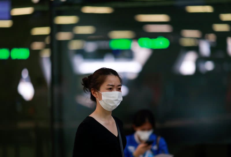 A tourist wears a mask to prevent the spread of the new coronavirus as she arrives at the Suvarnabhumi Airport in Bangkok