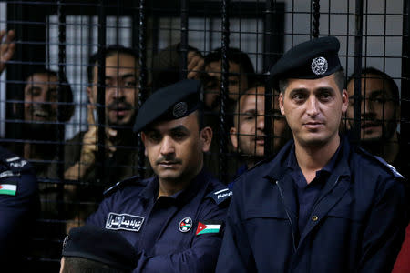 The accused react behind police officers during their trail for staging an attack on December 2016 on a Crusader castle in Kerak, at the State Security Court, in Amman, Jordan November 13, 2018. REUTERS/Muhammad Hamed