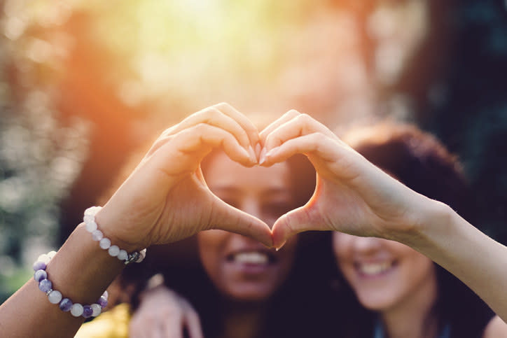 two girls making a heart with their hands