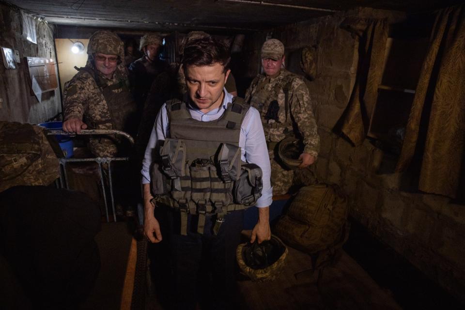 Ukrainian President Volodymyr Zelenskiy, center, stands inside a dugout as he visits the war-hit Luhansk region, eastern Ukraine, Monday, May 27, 2019. (Ukrainian Presidential Press Office via AP)