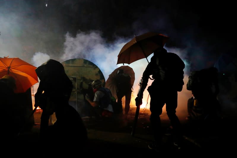 Anti-government protesters take cover during a standoff with riot police at the Chinese University of Hong Kong, Hong Kong