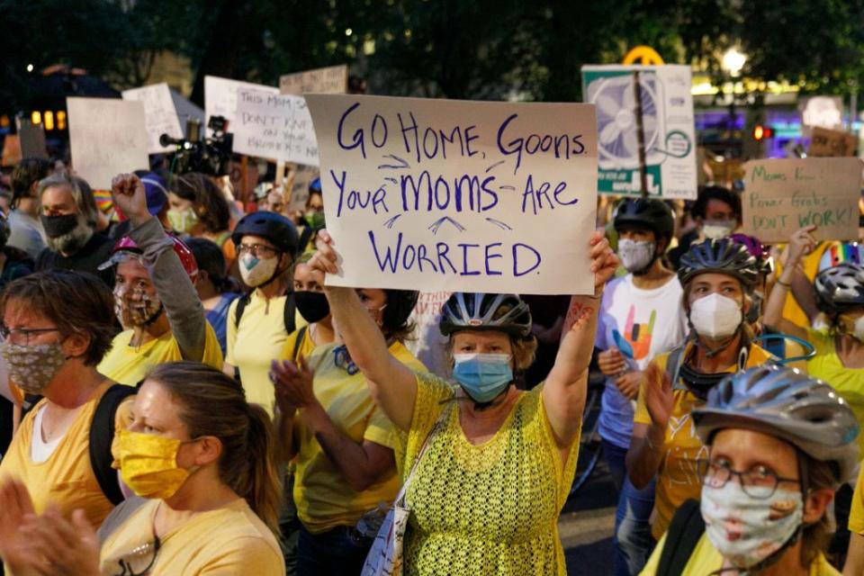 A woman holds a banner at the Portland Mom's March near the Justice Center in Portland, Oregon on July 21, 2020. (John Rudoff/Anadolu Agency via Getty Images)