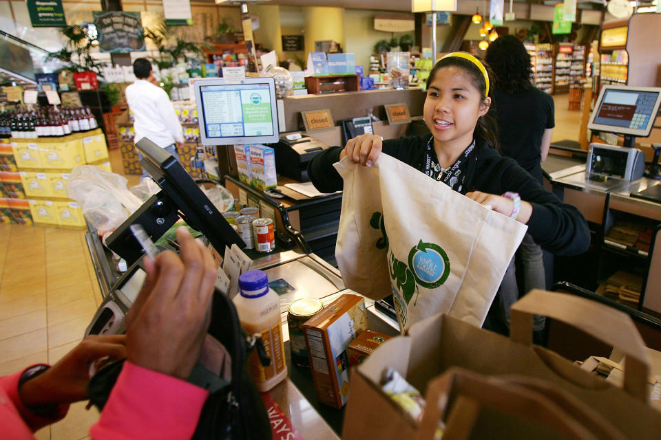 PASADENA, CA - APRIL 22:  Cashier Michelle Yulo hands out free reusable grocery bags at a Whole Foods Market natural and organic foods stores which is ending the use of disposable plastic grocery bags in its 270 stores in the US Canada and UK on Earth Day, April 22, 2008 in Pasadena California. The use of reusable bags has increased since a statewide plastic bag recycling law was enacted in July 2007 requiring grocers to provide in-store plastic bag recycling and to sell reusable shopping bags. Some communities have banned disposable single-use plastic shopping bags because they don?t break down in landfills, and clog waterways, endangering wildlife, and are a major source of litter.   (Photo by David McNew/Getty Images)