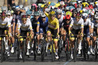 Slovenia's Tadej Pogacar, wearing the overall leader's yellow jersey, waves as he rides with his UAE Team Emirates teammates as they lead the pack during the twenty-first and last stage of the Tour de France cycling race over 108.4 kilometers (67.4 miles) with start in Chatou and finish on the Champs Elysees in Paris, France,Sunday, July 18, 2021. (AP Photo/Christophe Ena)