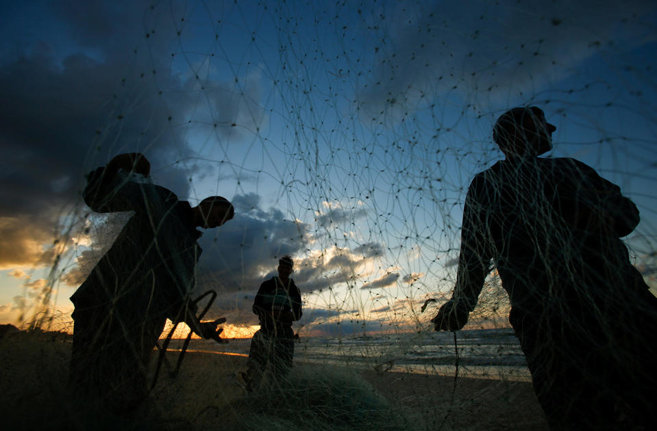 Palestinian fishermen fix their net at beach of northern of Gaza Strip