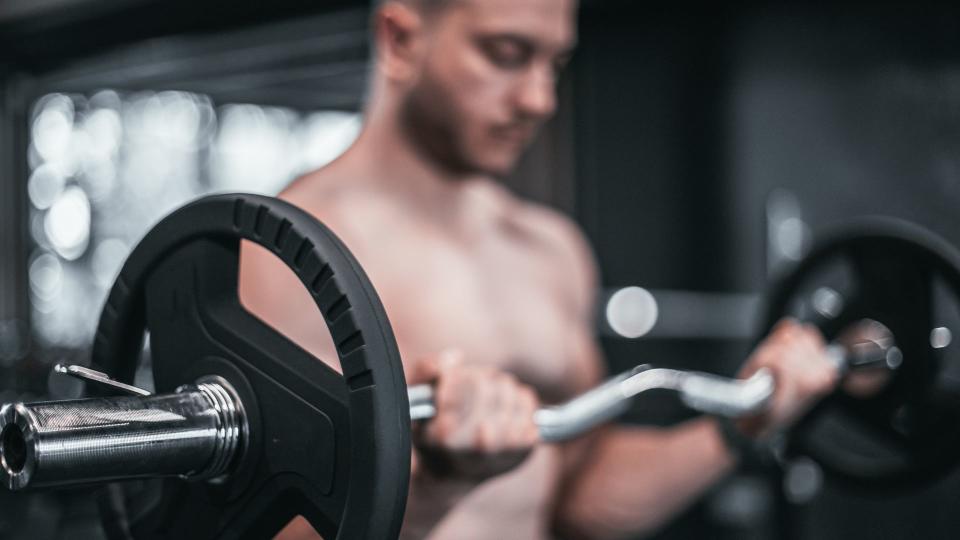 A man performing a bicep curl using an EZ bar