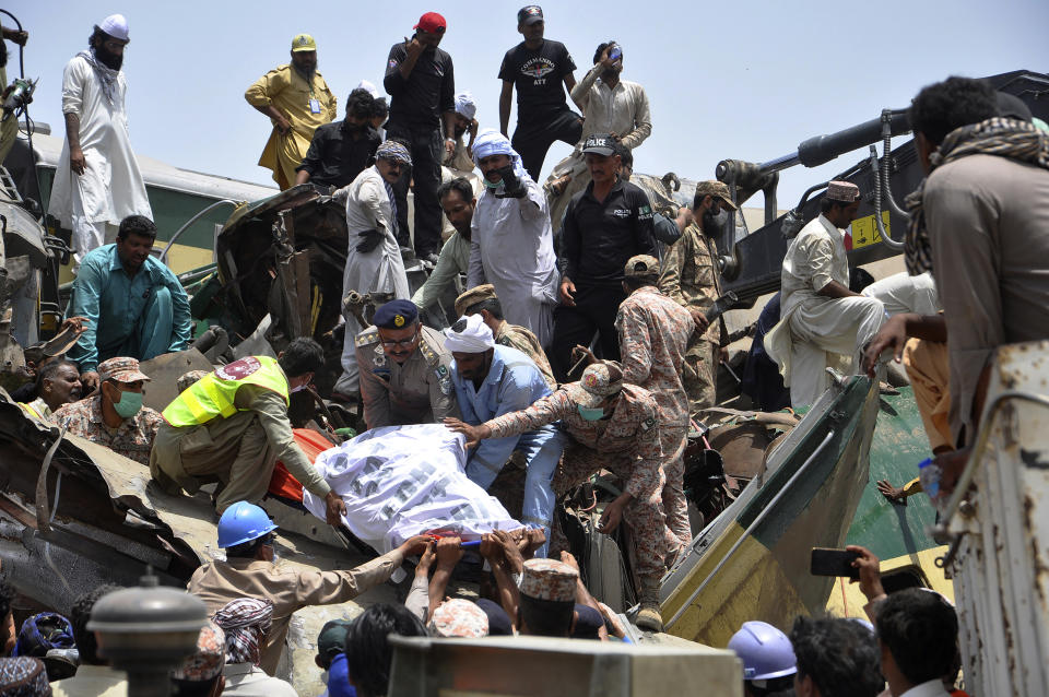 Soldiers and volunteers recover a body from the wreckage at the site of a train collision in Ghotki district, southern Pakistan, Monday, June 7, 2021. Two express trains collided in southern Pakistan early Monday, killing dozens of passengers, authorities said, as rescuers and villagers worked to pull injured people and more bodies from the wreckage. (AP Photo/Waleed Saddique)