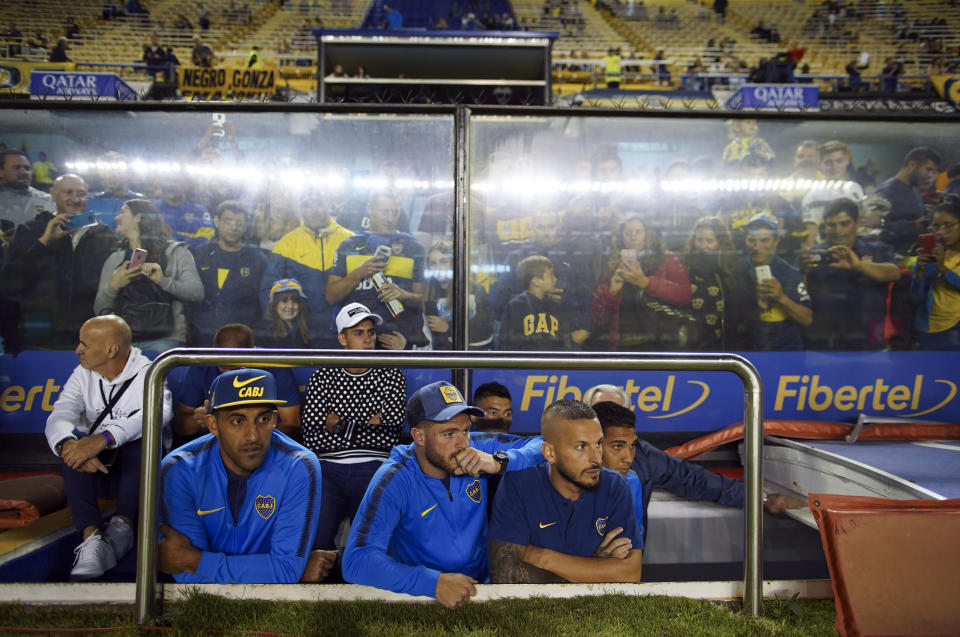 Boca Juniors', from left, Ramon Abila, Nahitan Nandez and Dario Benedetto watch the Superliga women's soccer tournament between Boca Juniors and Lanus in Buenos Aires, Argentina, Saturday, March 9, 2019. The women competed in one of Argentina's most famous stadiums on Saturday, a milestone for the female players who are fighting for the same rights as male soccer players in the country's most popular sport. (AP Photo/Natacha Pisarenko)