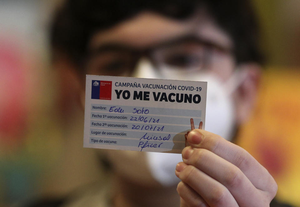 Edu Soto, 15, shows his vaccination card to the camera after getting a first dose of the Pfizer vaccine for COVID-19 at the Teleton Institute, a clinic that specializes in treating chronically ill children in Santiago, Chile, Tuesday, June 22, 2021, on the first day the government started vaccinating youths between ages 12 and 17 who have chronic illnesses. (AP Photo/Esteban Felix)