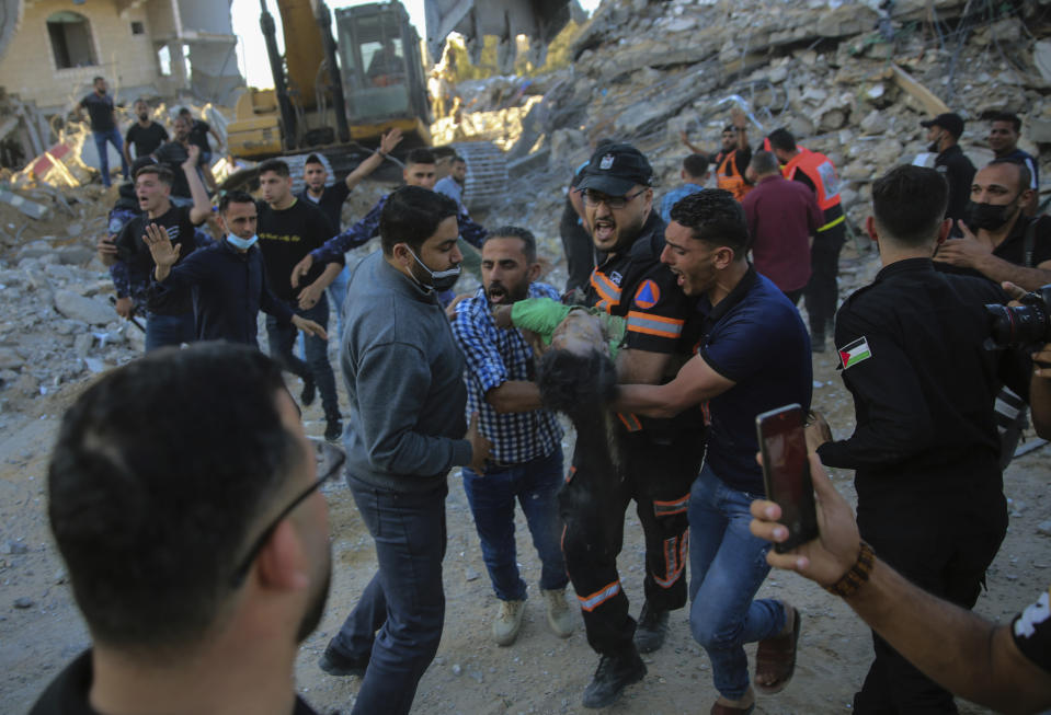 Palestinians carry the body of a child found in the rubble of a house belonging to the Al-Tanani family, that was destroyed in Israeli airstrikes in town of Beit Lahiya, northern Gaza Strip, Thursday, May 13, 2021. (AP Photo/Abdel Kareem Hana)