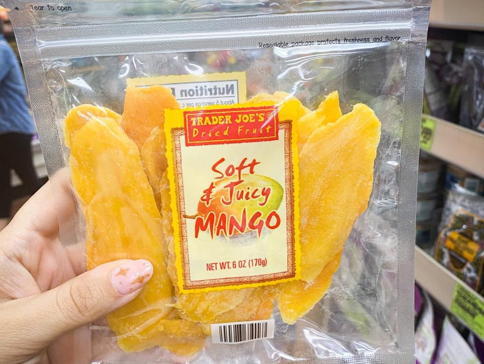 hand holding package of dried mango in an aisle at trader joes