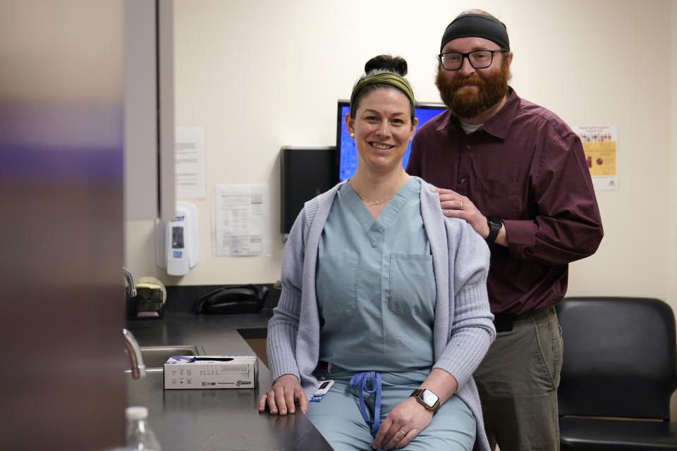 Dr. Caitlin Robinson, D.O., left, and her husband Stephen J. Robinson, M.D., right, pose for a photo at a Chesapeake Health Care office in Salisbury, Md., Thursday, March 2, 2023. (AP Photo/Susan Walsh)