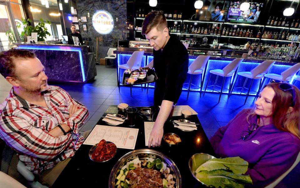 Manager Drew Leverton, center, serves customers Travis Shutz, left, and Jeanette McDermith at Empire Korean Steakhouse in Springfield on Thursday. The restaurant will be open on Christmas Day.