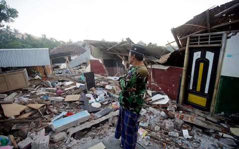 A man inspects the ruin of his house destroyed by an earthquake in North Lombok, Indonesia - Credit: Firdia Lisnawati/ AP