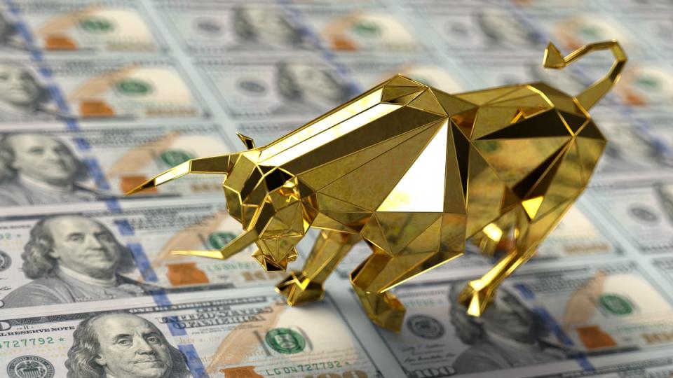 A golden bull on top of sheets of U.S. $100 bills.
