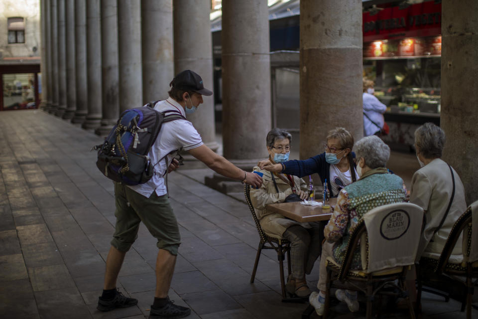 A woman gives alms to a beggar as they sit in a bar terrace during the coronavirus outbreak in Barcelona, Spain, Thursday, June 5, 2020. (AP Photo/Emilio Morenatti)