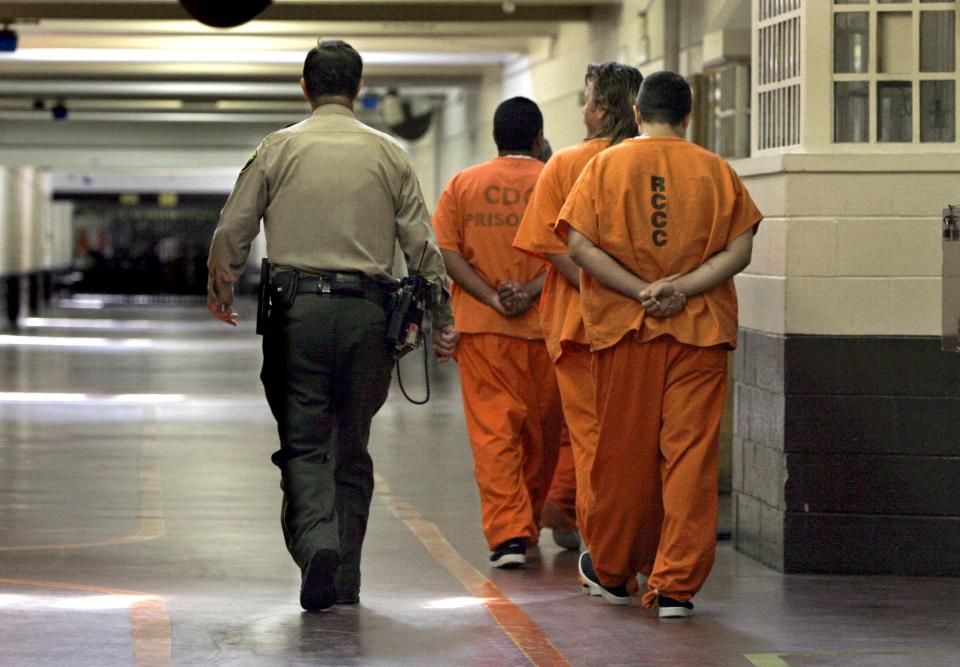 A correctional officer escorts a group of recently arrived inmates through the Deuel Vocational Institution in Tracy, California.