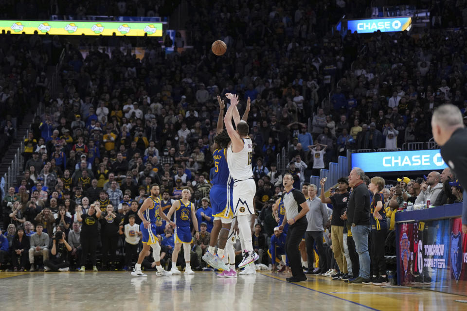 Denver Nuggets center Nikola Jokic (15) hits a 3-pointer over Golden State Warriors forward Kevon Looney (5) to give the Nuggets the win in an NBA basketball game Thursday, Jan. 4, 2024, in San Francisco. (AP Photo/Loren Elliott)