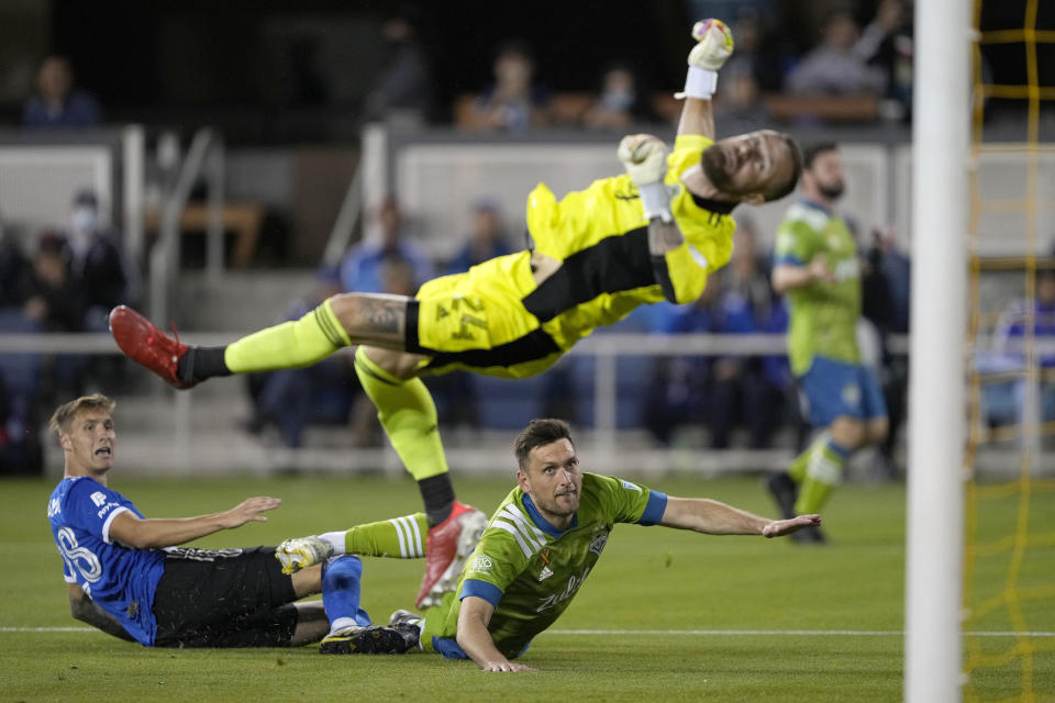San Jose Earthquakes forward Benji Kikanovic, left, scores a goal over Seattle Sounders defender Shane O'Neill, center, and goalkeeper Stefan Frei, top, during the second half of an MLS soccer match Wednesday, Sept. 29, 2021, in San Jose, Calif. (AP Photo/Tony Avelar)