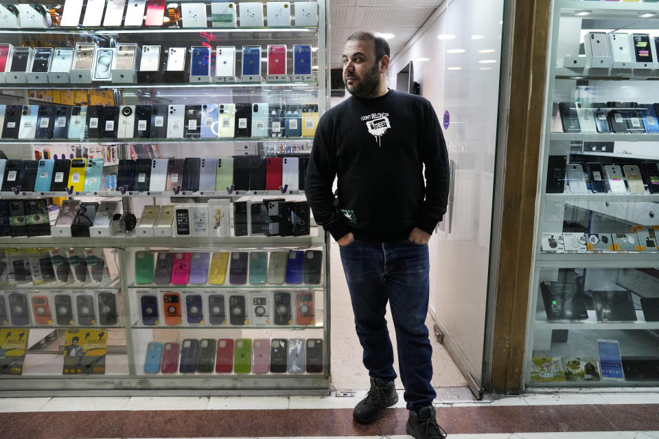 A cellphone vendor waits for customer as he stands outside his shop in downtown Tehran, Iran, Wednesday, Feb. 21, 2024. Even though Supreme Leader Ayatollah Ali Khamenei has denounced American luxury goods amid years of tensions with the West, consumers still want the phones and the prestige associated with them. (AP Photo/Vahid Salemi)