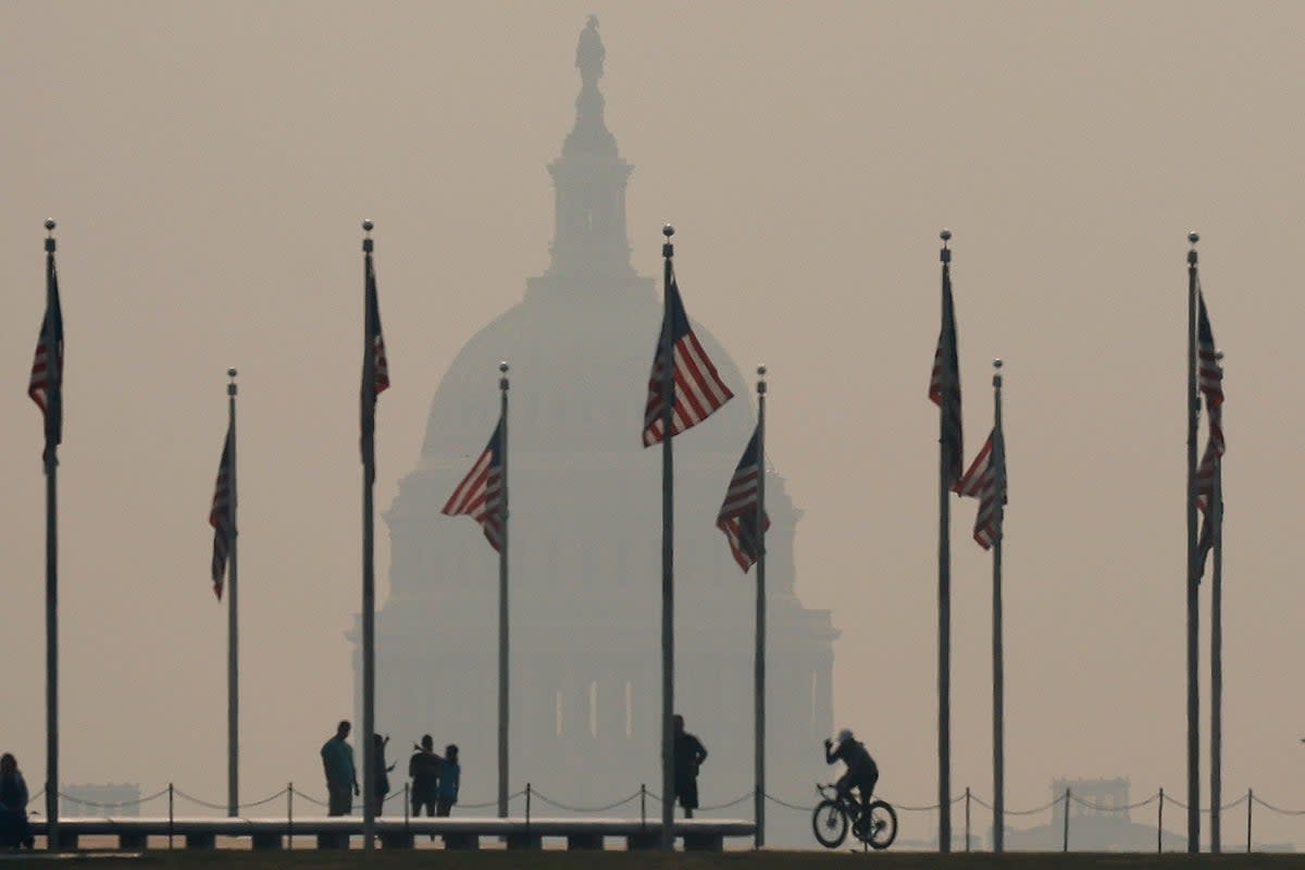 Tourists walk around the base of the Washington Monument as wildfire smoke casts a haze of the US Capitol on the National Mall on June 07, 2023 in Washington, DC (Getty Images)