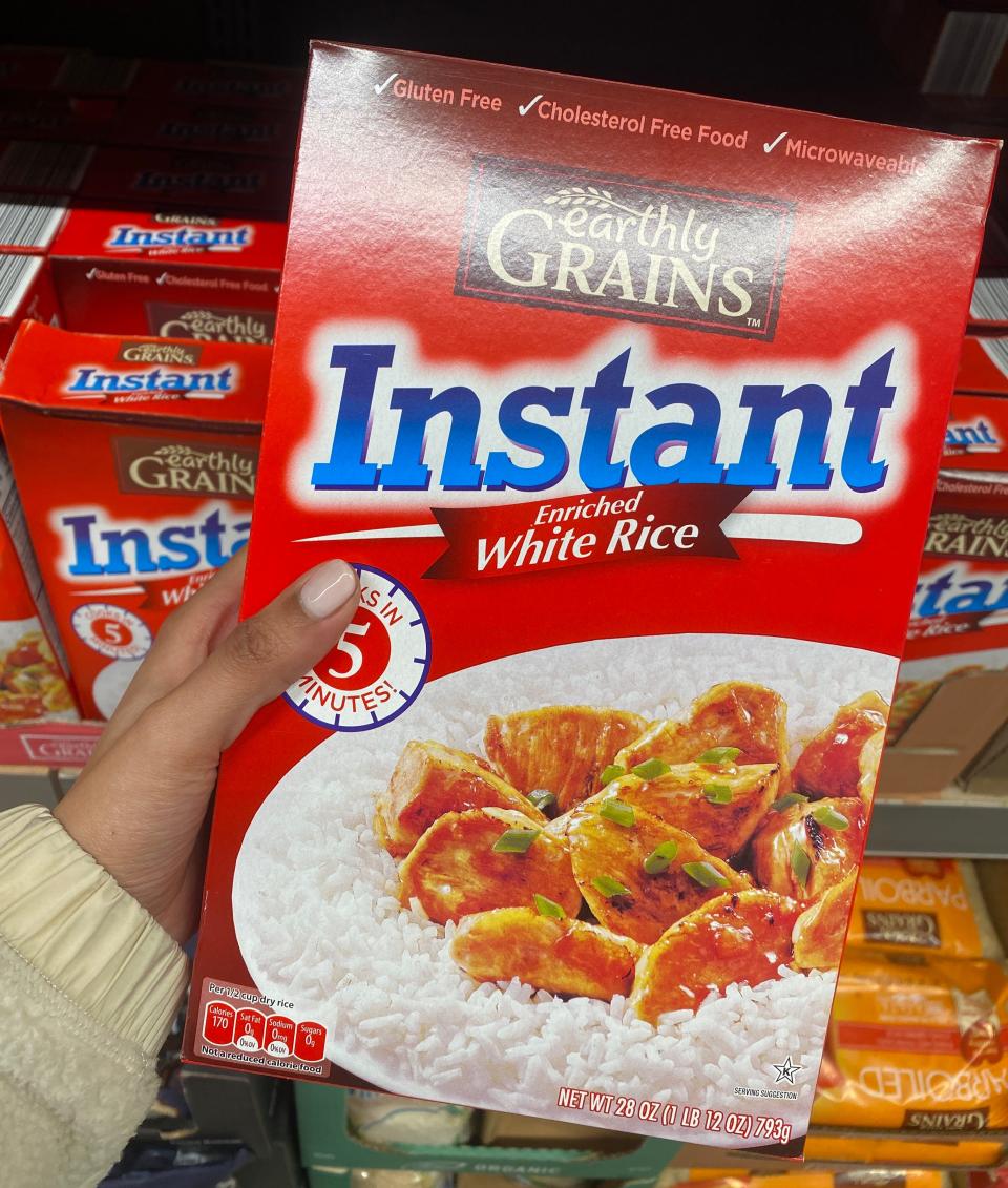 Hand holding red box of instant rice at Aldi