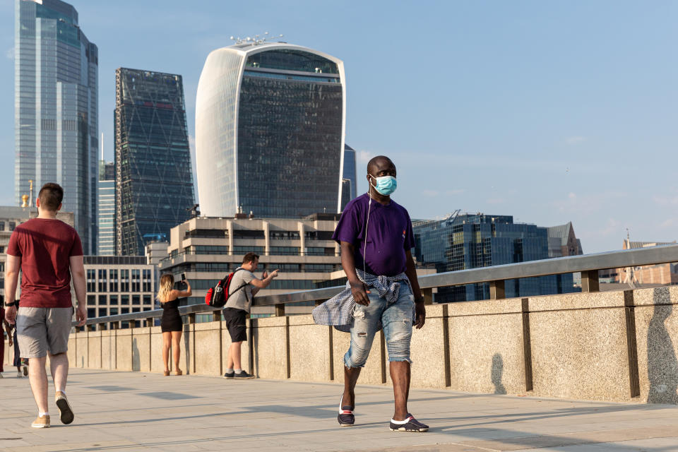 Tourists are seen walking on London Bridge at south bank of Thames river as London encourages internal tourism after global Coronavirus lockdown drastically shrunk international tourism - London, England, August 9, 2020. While England introduces a policy of obligatory protective face masks in closed public spaces, some people choose to use masks outdoors too. (Photo by Dominika Zarzycka/NurPhoto via Getty Images)