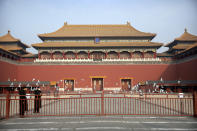 In this Monday, Jan. 27, 2020 photo, security officials wearing face masks stand as a flock of pigeons fly past closed gates at the entrance to the Forbidden City, normally crowded with tourists during the Lunar New Year holiday, in Beijing. Fears of a virus outbreak have kept many indoors and at home in China's capital. Cultural landmarks such as the Great Wall and Forbidden City have closed their doors to visitors, nearly deserted shopping malls have reduced their operating hours, and restaurants that remain open draw just a handful of customers. (AP Photo/Mark Schiefelbein)