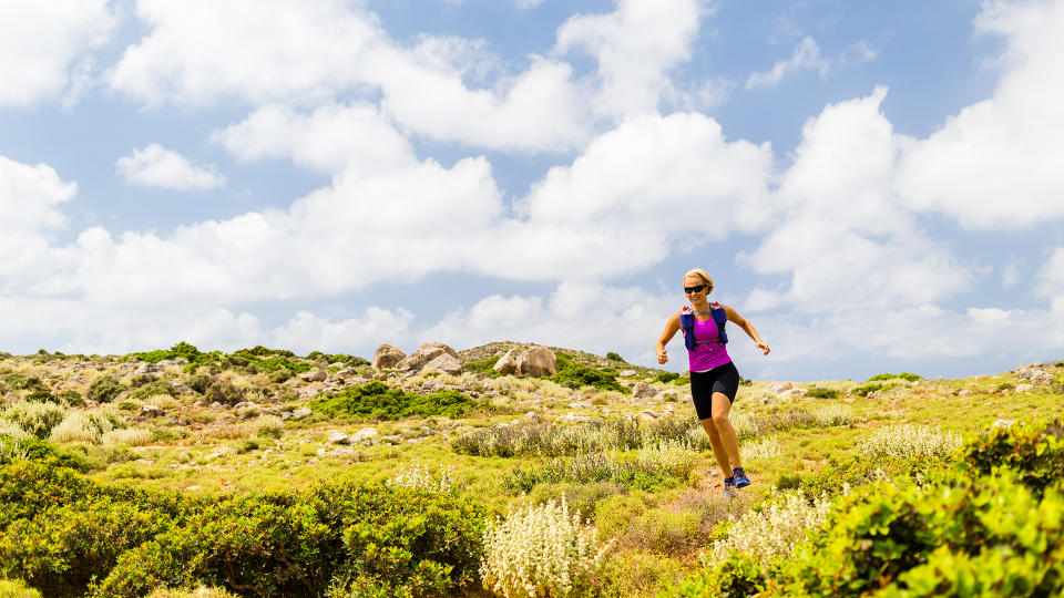 A woman running across a sunny field